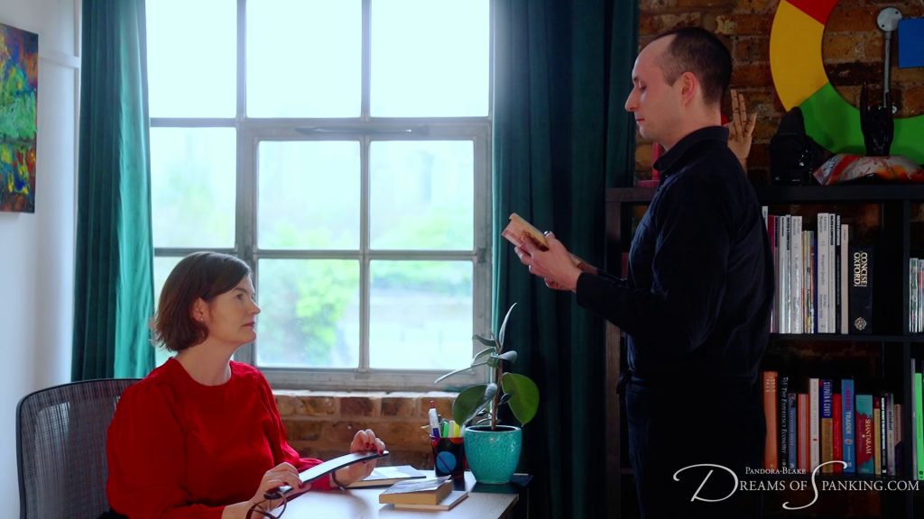 Vee reads aloud from the filthy book as the librarian holds a strap