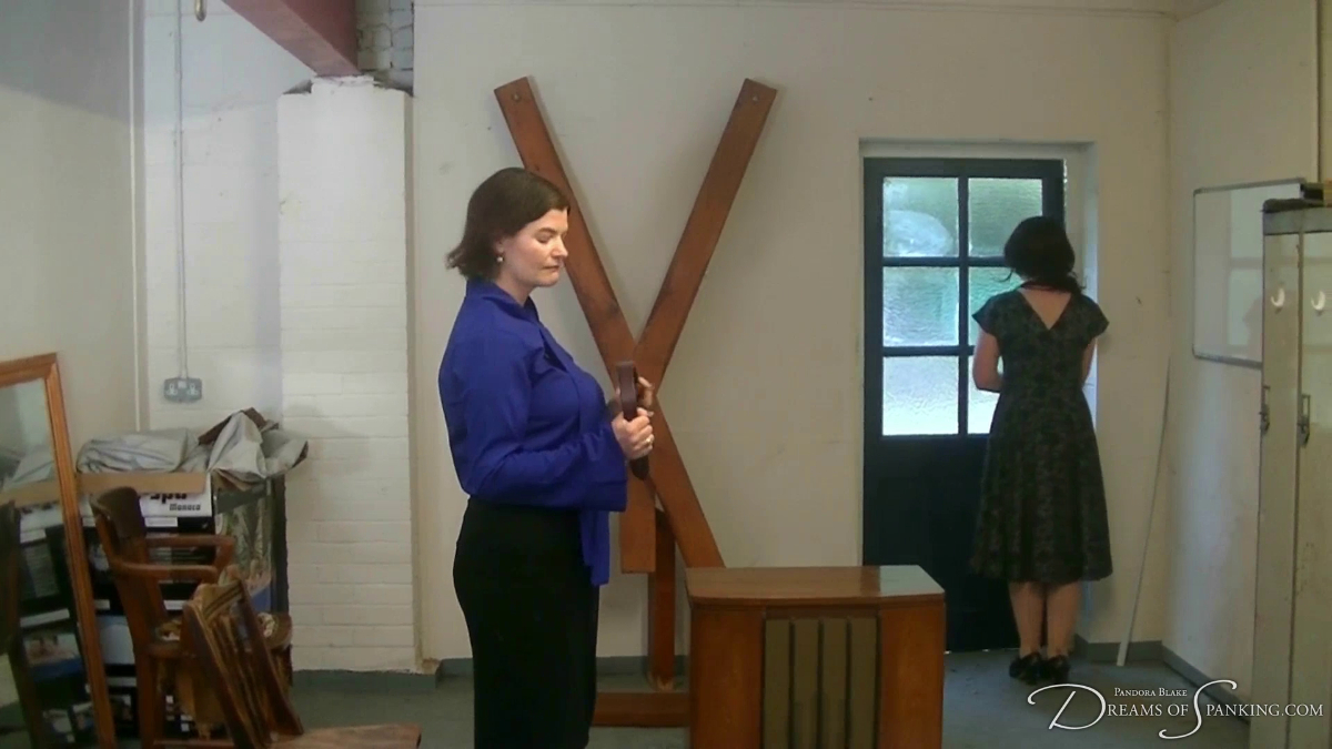 The school bursar leaves folloing her punishment as Miss Cavendish looks on holding a wooden paddle