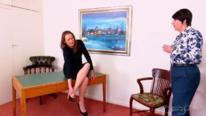 Matilda sits on the desk to rest her painful feet wearing high black heels as she talks to Pandora