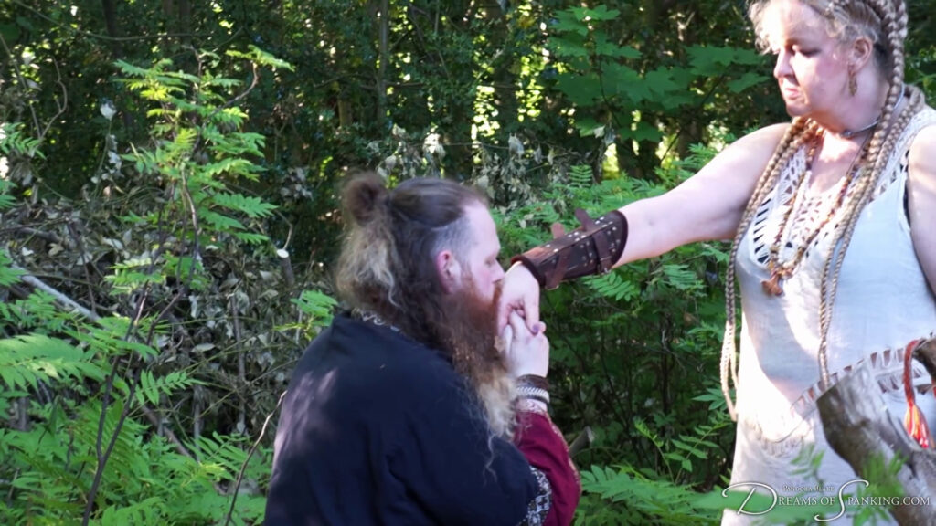 Jamie kneels and kisses his queen's hand after his punishment