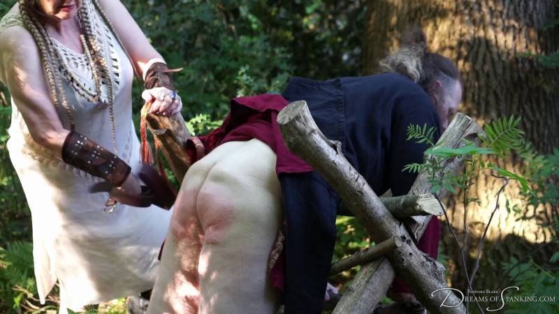 Jamie bends over in the woods, bare bottom exposed for his punishment from the Queen