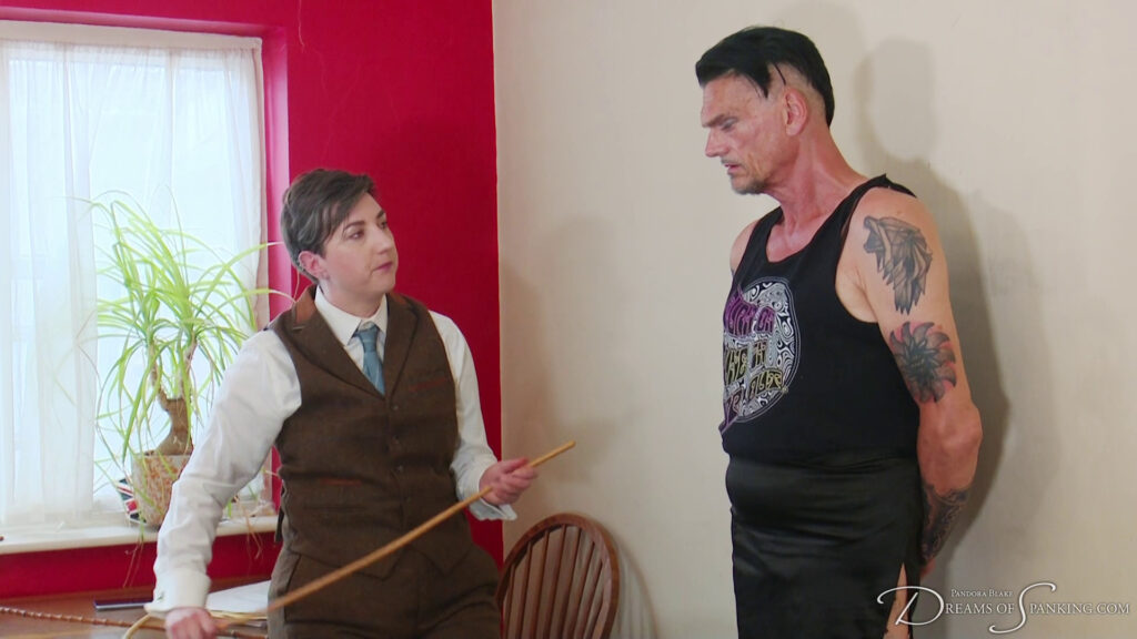 Blake holds a cane and looks up at Pippa before their punishment