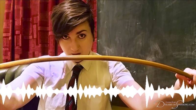 A person wearing school uniform with short dark hair holds up a cane in front of them.